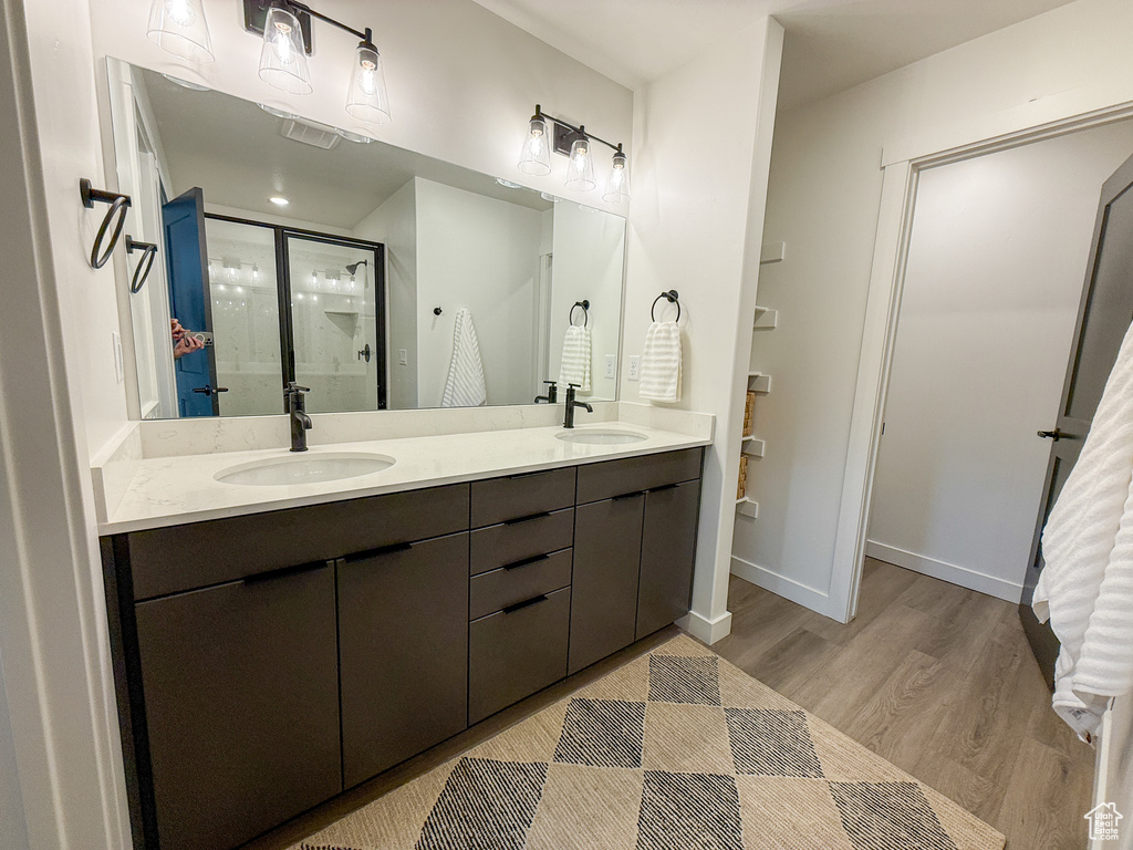 Full bath with wood finished floors, a sink, a stall shower, and double vanity
