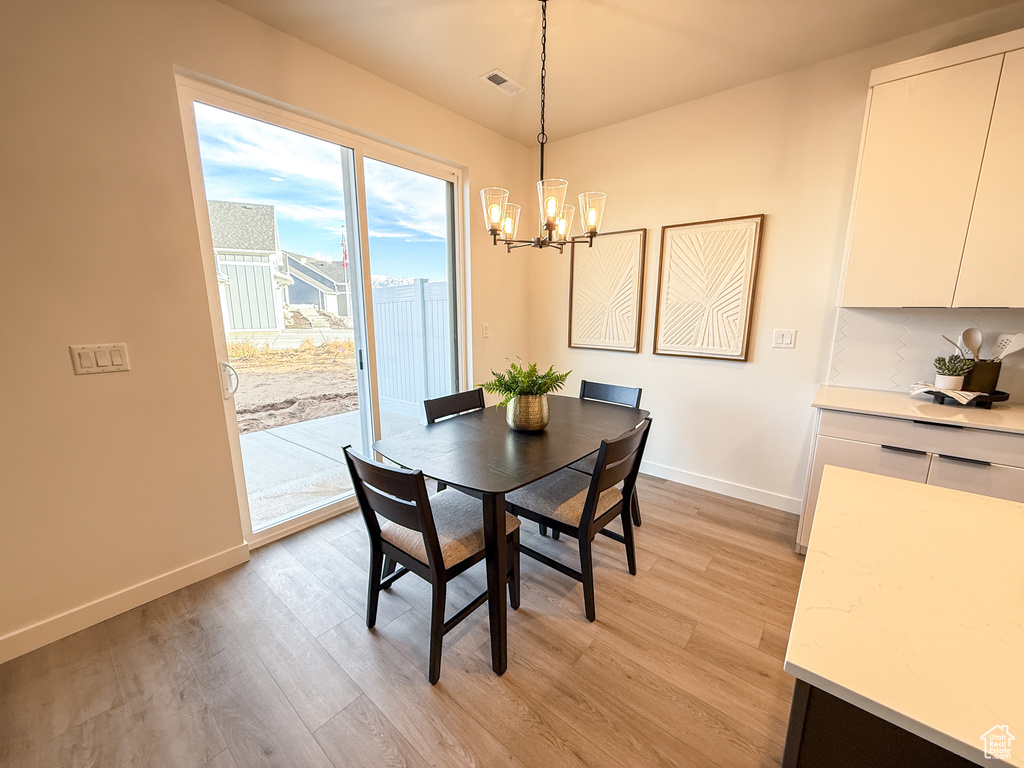 Dining room with baseboards, a notable chandelier, visible vents, and light wood-style floors