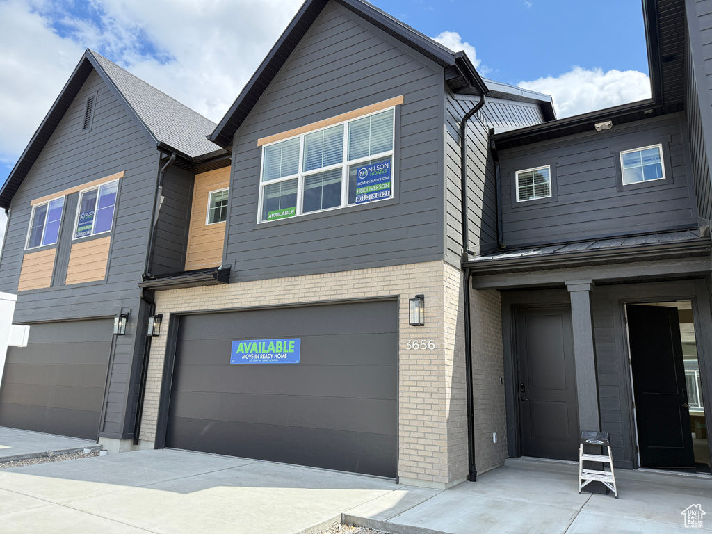 View of front of house with an attached garage and brick siding