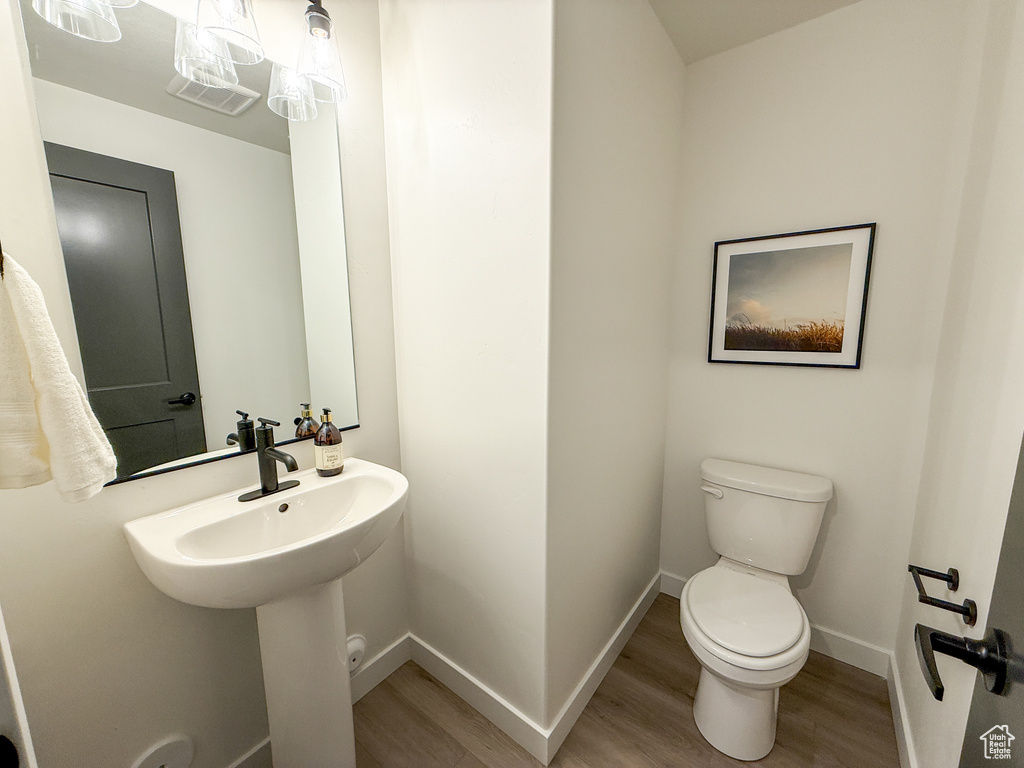 Half bath featuring toilet, baseboards, and wood finished floors