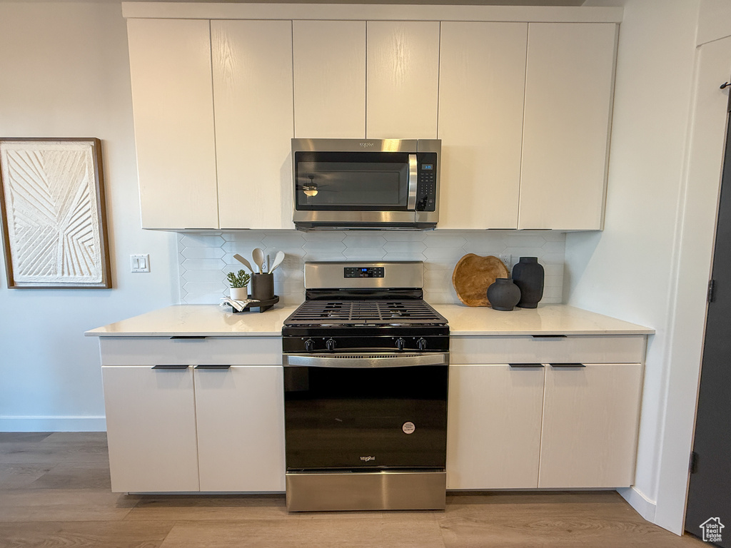Kitchen featuring baseboards, light countertops, light wood-style flooring, and stainless steel appliances