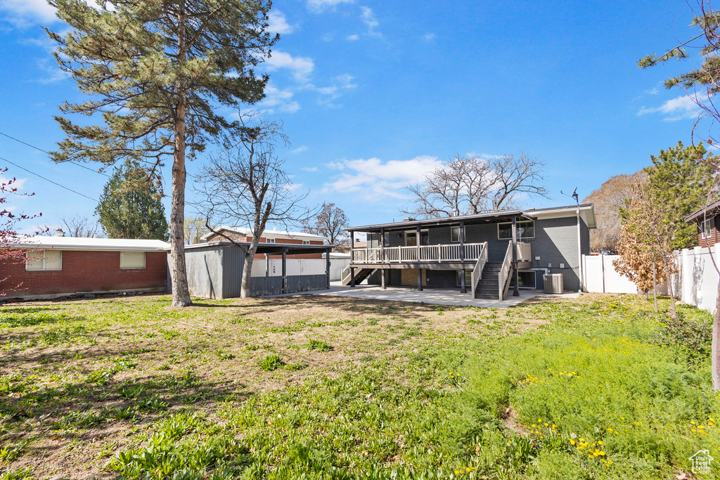 Rear view of house with central AC, a yard, a fenced backyard, stairway, and a deck