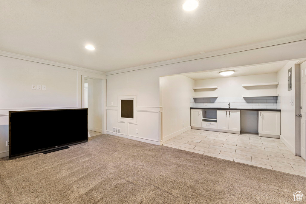 Unfurnished living room featuring light tile patterned floors, light colored carpet, visible vents, recessed lighting, and a sink