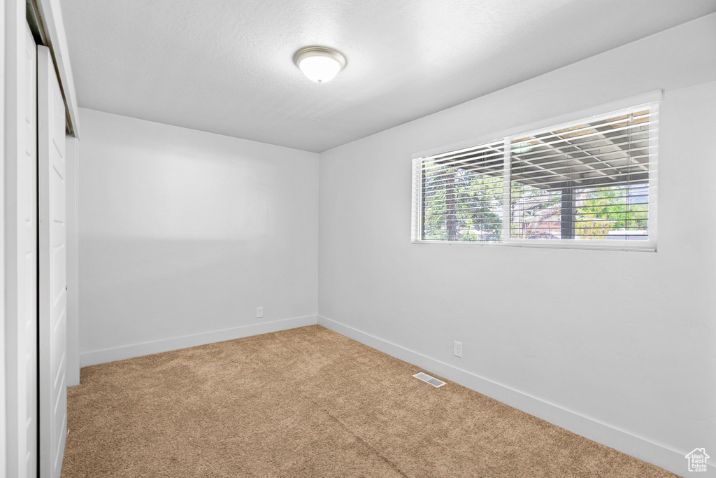 Unfurnished room featuring baseboards, visible vents, and carpet