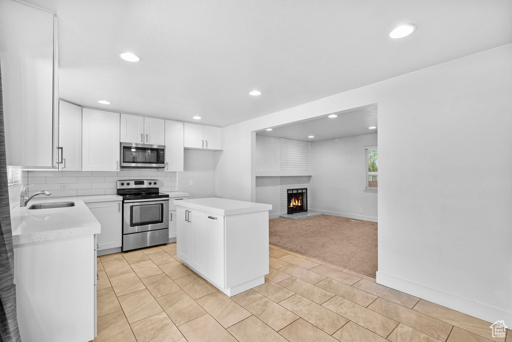 Kitchen with a sink, light countertops, a center island, stainless steel appliances, and recessed lighting