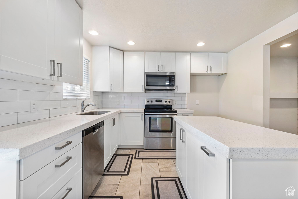 Kitchen with stainless steel appliances, white cabinets, and a sink
