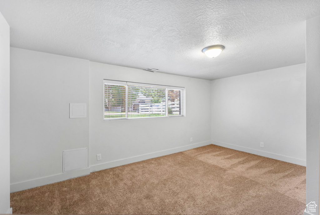 Unfurnished room featuring baseboards, carpet flooring, a textured ceiling, and visible vents
