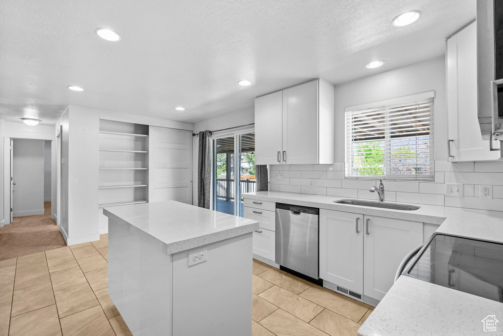 Kitchen featuring a sink, dishwasher, a center island, recessed lighting, and white cabinetry