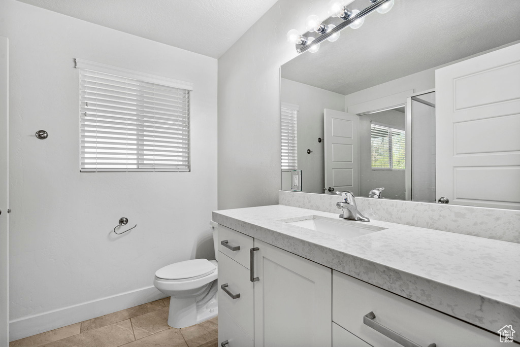 Bathroom featuring tile patterned flooring, vanity, a shower, toilet, and baseboards