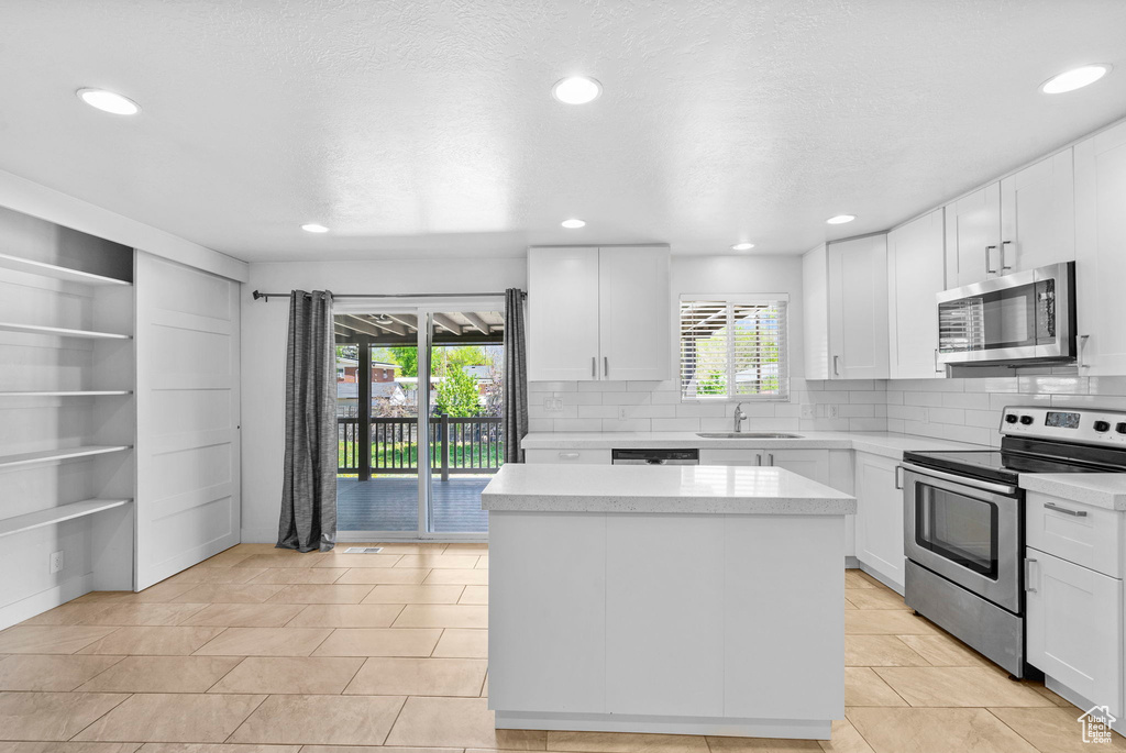 Kitchen with a sink, decorative backsplash, appliances with stainless steel finishes, and a kitchen island
