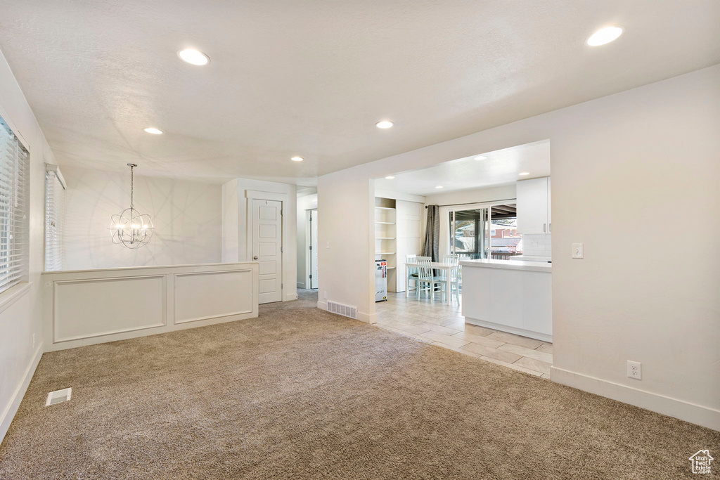 Unfurnished room with baseboards, an inviting chandelier, light carpet, recessed lighting, and visible vents