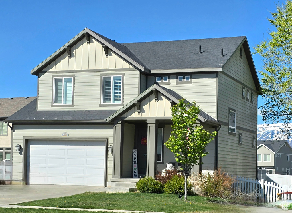 Craftsman house featuring an attached garage, board and batten siding, fence, and driveway