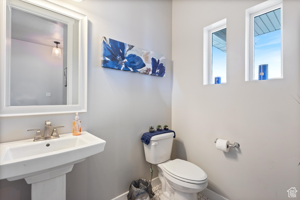 Half bath featuring baseboards, a sink, and toilet
