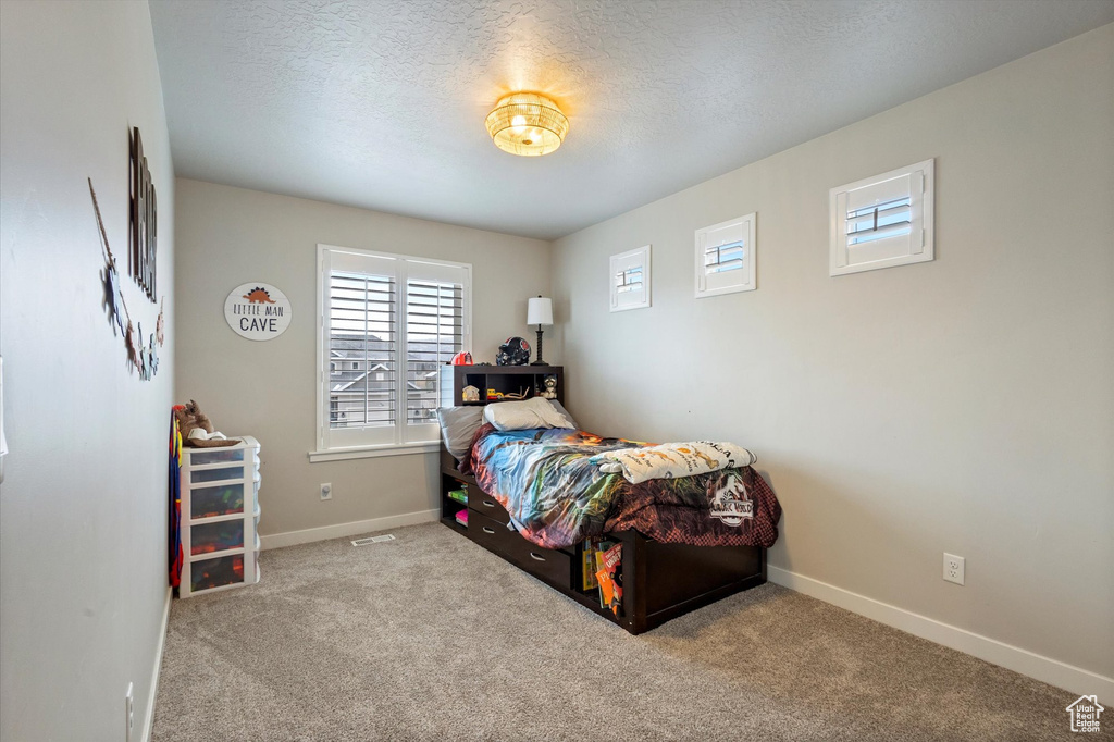 Bedroom with carpet floors, a textured ceiling, and baseboards