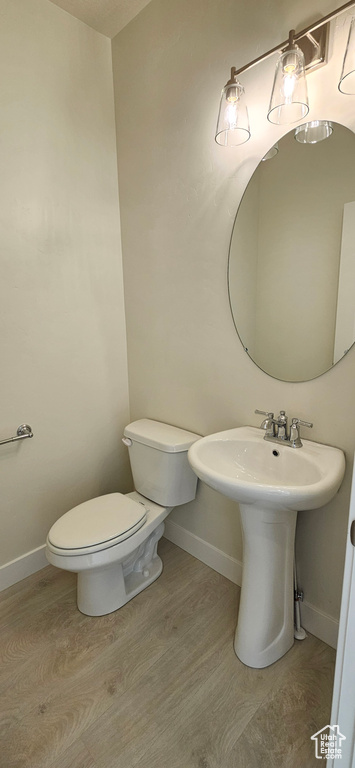 Half bath with toilet and wood finished floors