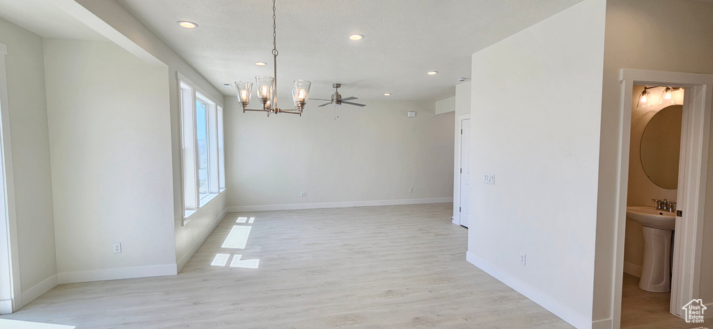 Empty room with a chandelier, recessed lighting, light wood-style flooring, and ceiling fan