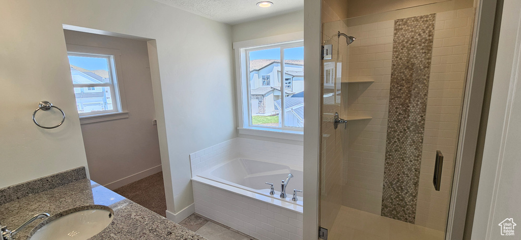 Full bathroom with a shower stall, a bath, healthy amount of natural light, and a textured ceiling