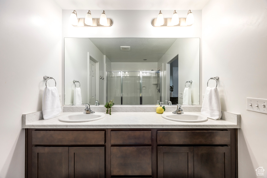 Bathroom with a sink, a stall shower, and double vanity