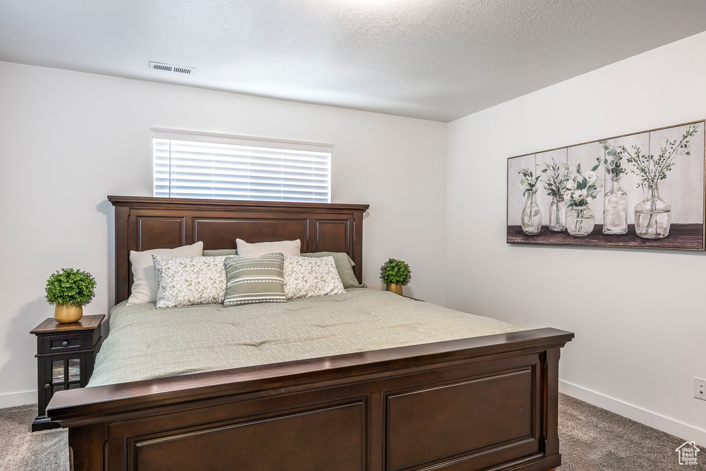 Carpeted bedroom featuring baseboards and visible vents