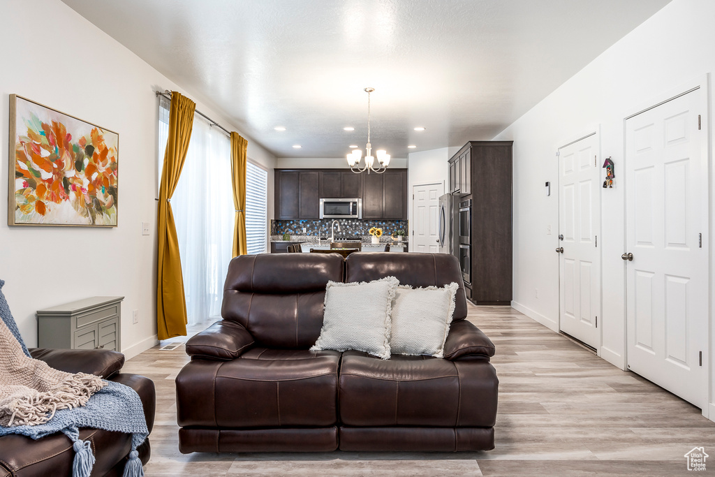 Living area with light wood-type flooring, recessed lighting, baseboards, and a chandelier