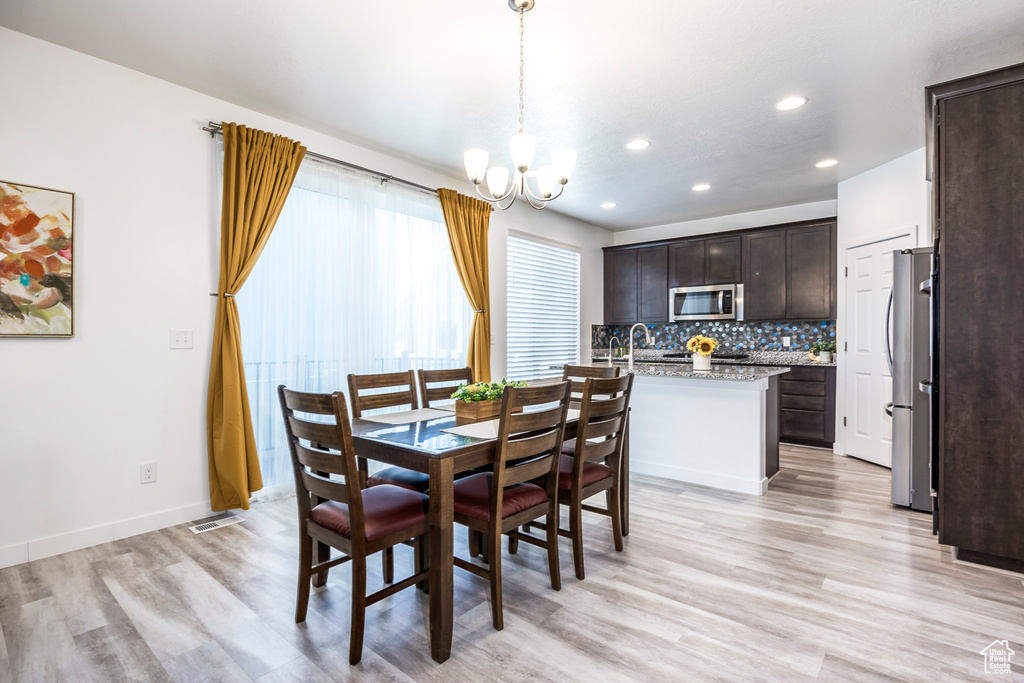 Dining space featuring recessed lighting, baseboards, a notable chandelier, and light wood-type flooring