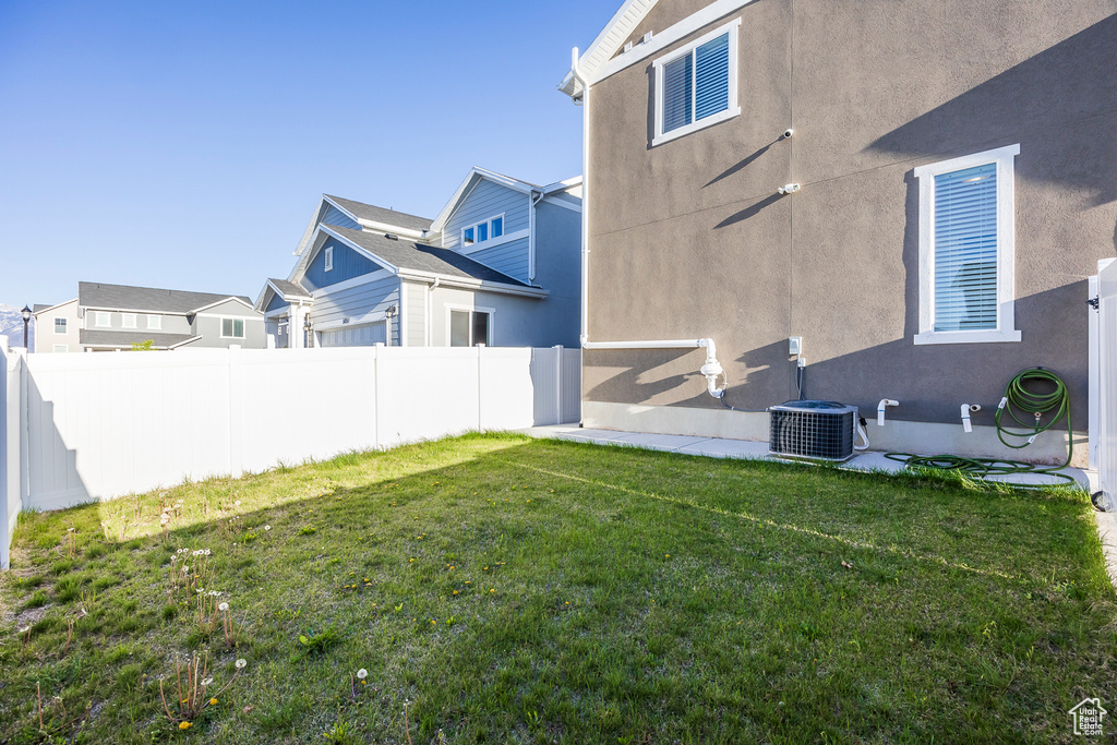 View of yard with central air condition unit, fence, and a residential view