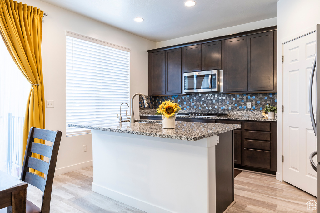 Kitchen featuring plenty of natural light, appliances with stainless steel finishes, light stone counters, and backsplash