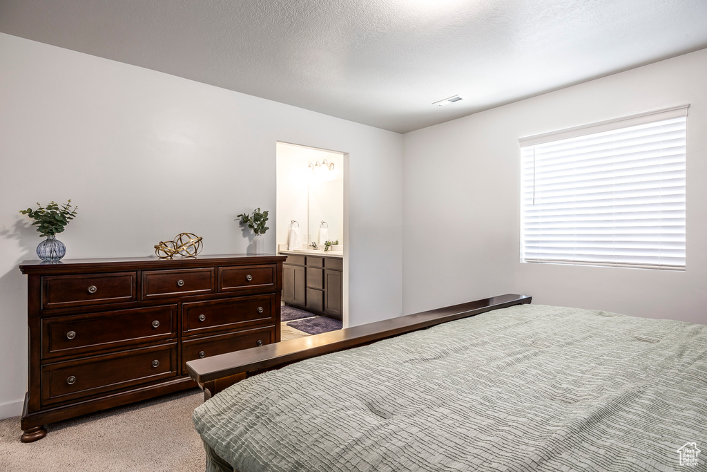 Bedroom featuring ensuite bath and light carpet