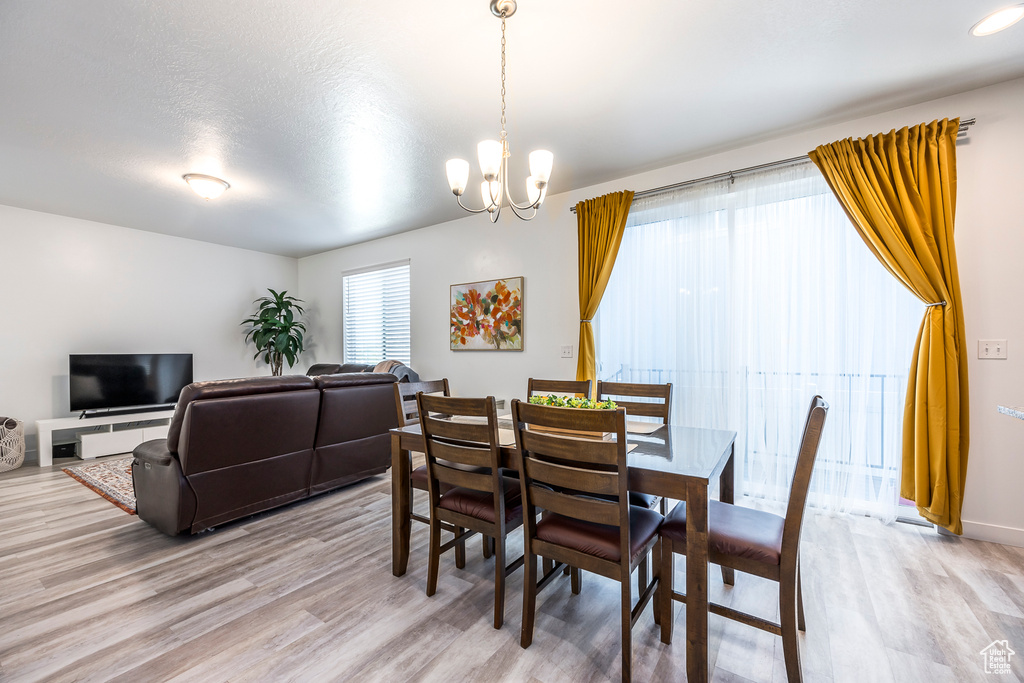 Dining room with light wood-style floors and a notable chandelier