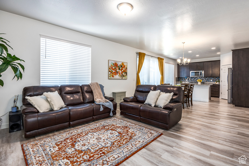 Living area with recessed lighting, light wood-style flooring, and a notable chandelier