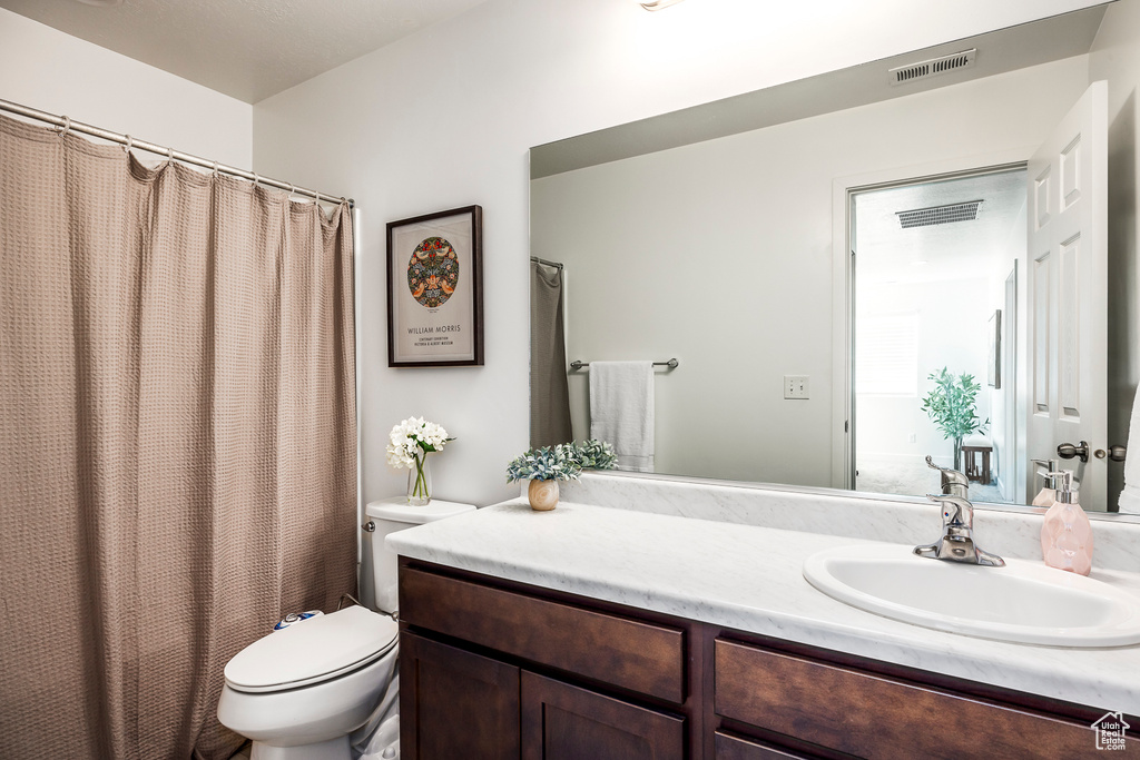 Full bath featuring toilet, visible vents, and vanity