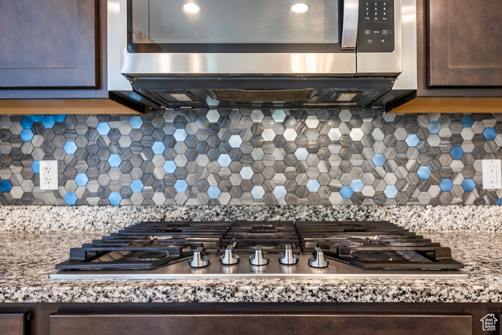Room details featuring decorative backsplash, dark brown cabinets, and stainless steel appliances