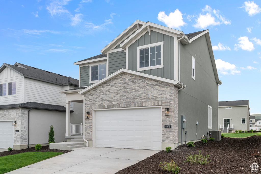 View of front facade with central AC, driveway, board and batten siding, stone siding, and an attached garage