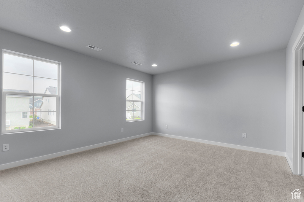 Empty room featuring light carpet, baseboards, and recessed lighting