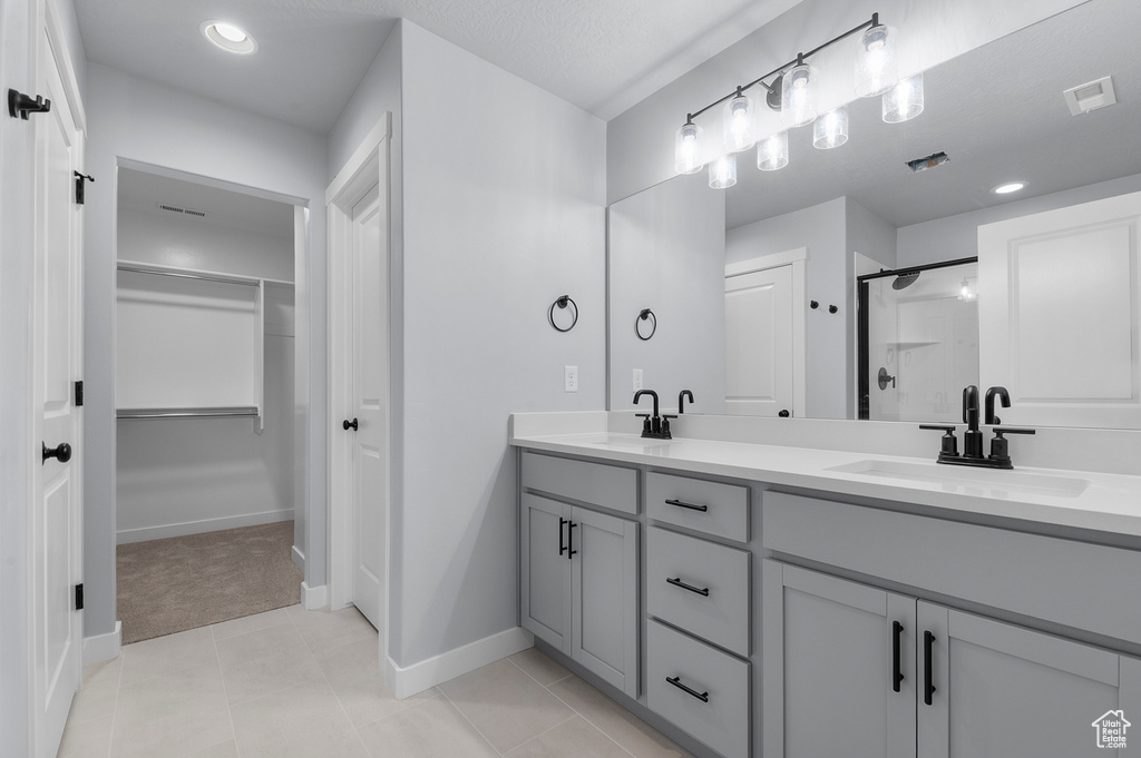 Bathroom with a stall shower, baseboards, double vanity, and a walk in closet