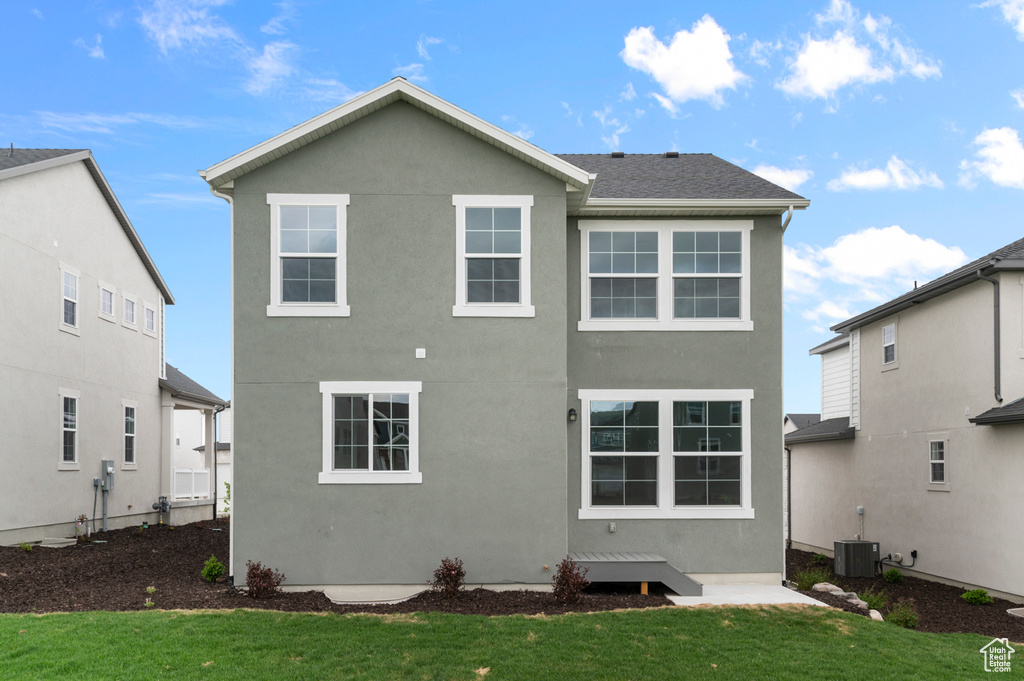 Back of house featuring a yard, stucco siding, and central air condition unit