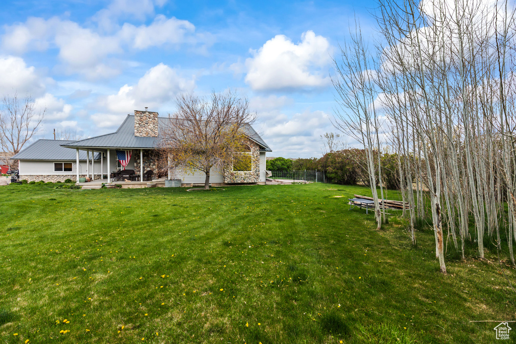 Back of property featuring a lawn, fence, a chimney, and metal roof