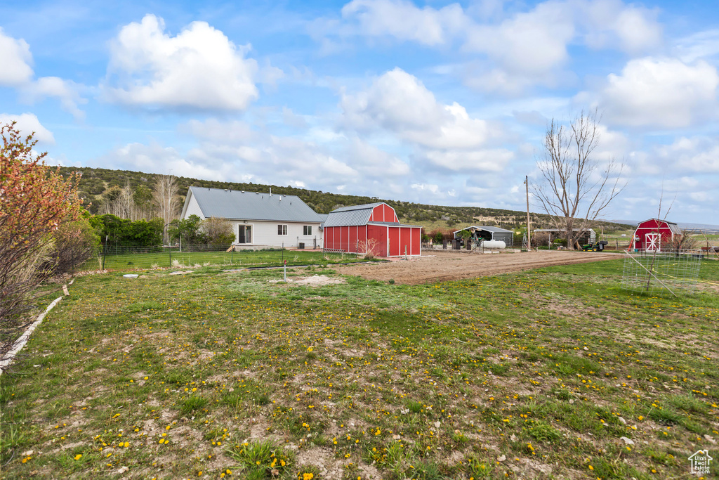 View of yard featuring a barn, fence, and an outbuilding