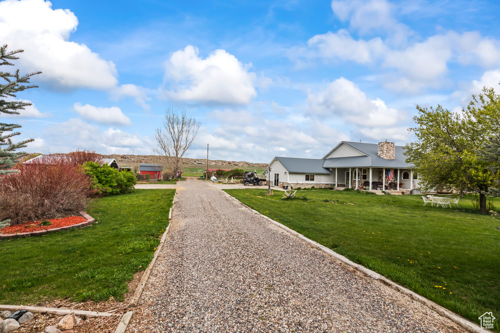 View of front of property with a porch, a front lawn, a chimney, and gravel driveway