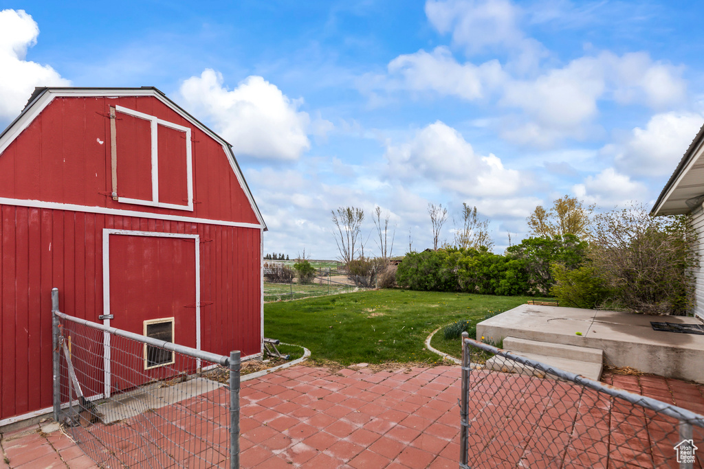 View of patio with a barn, fence, and an outbuilding