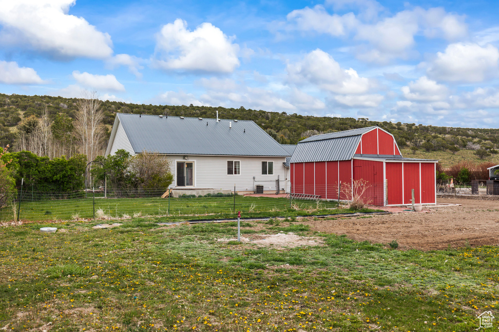Rear view of property with fence, a barn, a lawn, and metal roof