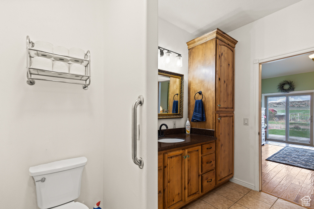 Bathroom featuring vanity, baseboards, tile patterned floors, and toilet