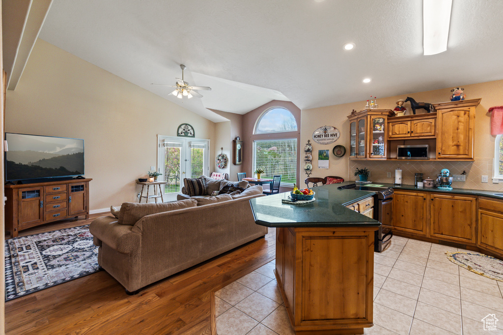 Kitchen featuring dark countertops, open floor plan, ceiling fan, a center island, and brown cabinets