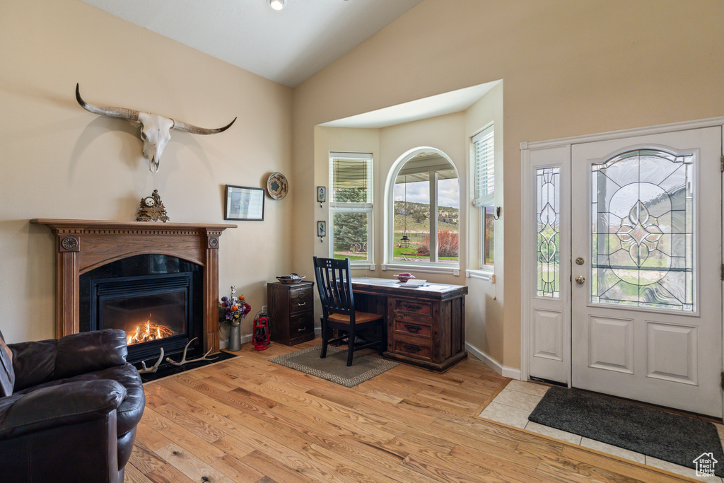 Home office featuring a fireplace with flush hearth, wood finished floors, and lofted ceiling