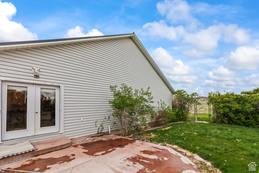 View of side of home featuring a lawn, a patio area, and french doors