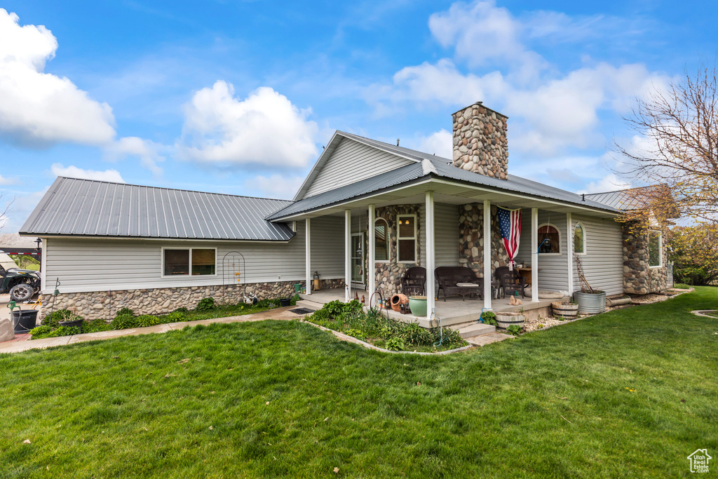 View of front facade featuring a chimney, a front lawn, metal roof, and stone siding
