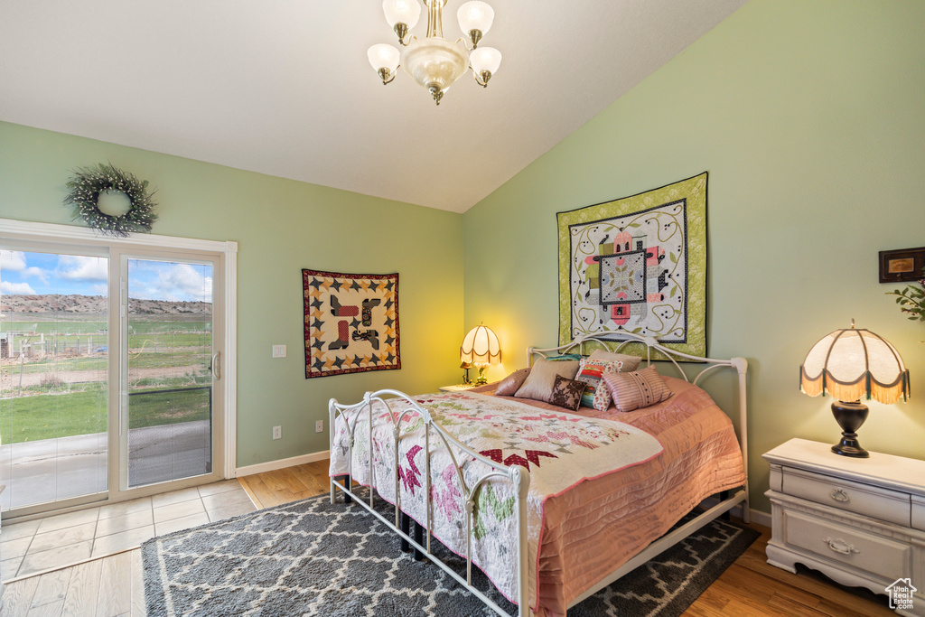 Bedroom featuring a chandelier, access to exterior, baseboards, lofted ceiling, and light wood-style floors