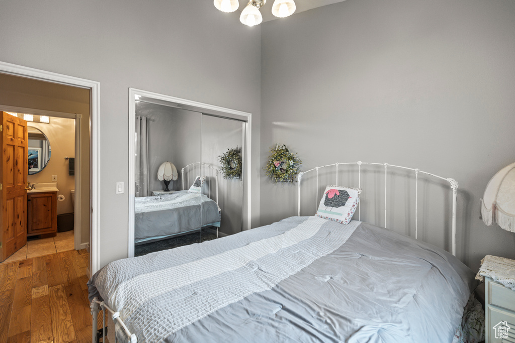 Bedroom with an inviting chandelier, wood finished floors, and a closet