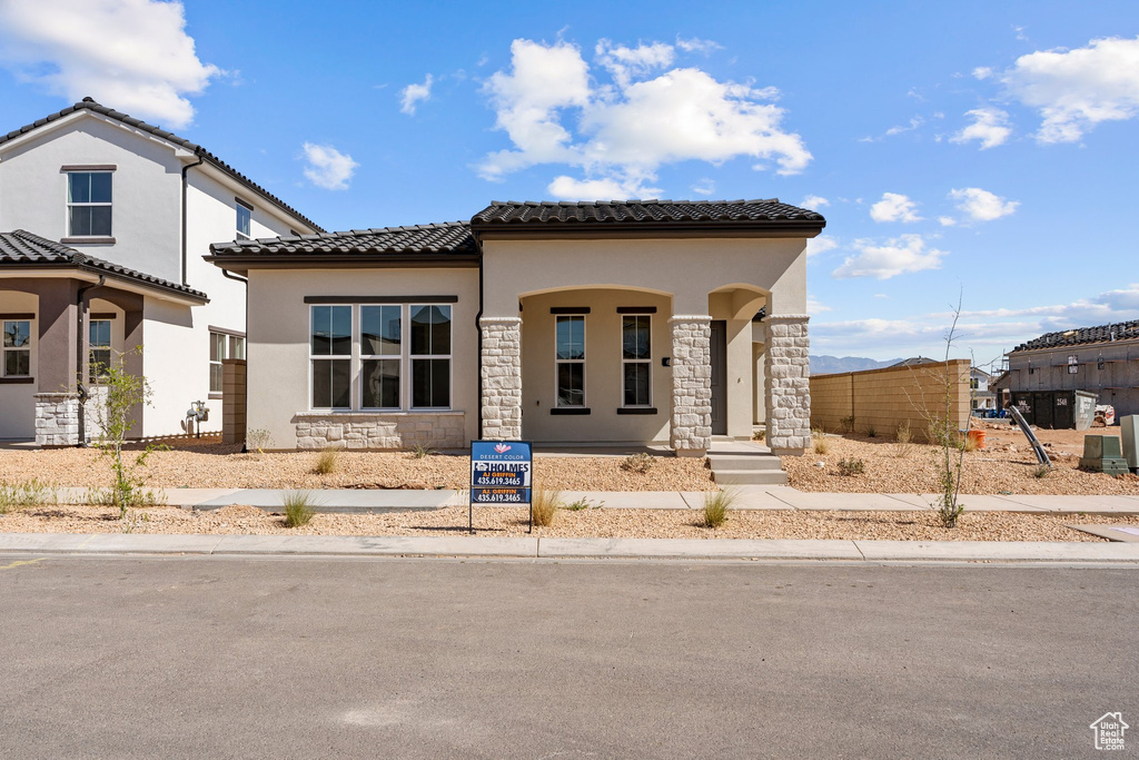 Mediterranean / spanish-style home with stucco siding, a tile roof, and stone siding