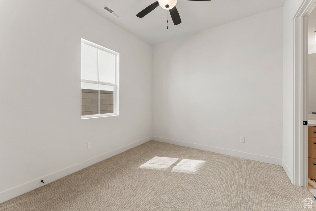 Empty room with baseboards, ceiling fan, light carpet, and visible vents